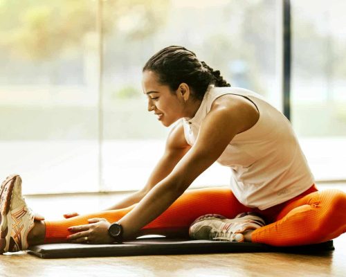 A woman enjoying a yoga stretch indoors, promoting a healthy lifestyle.