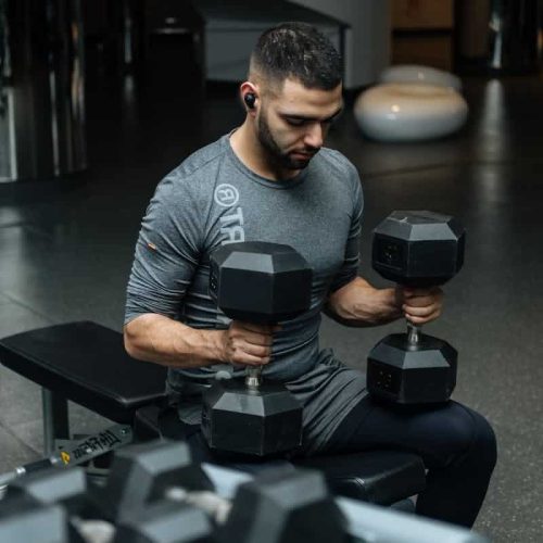 Adult man lifting dumbbells in a gym, focused on strength training workout.