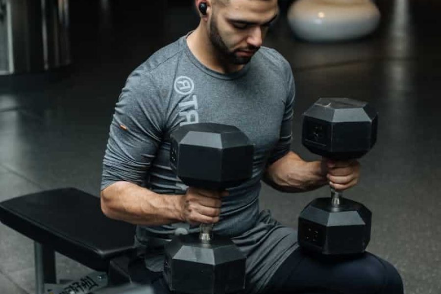 Adult man lifting dumbbells in a gym, focused on strength training workout.