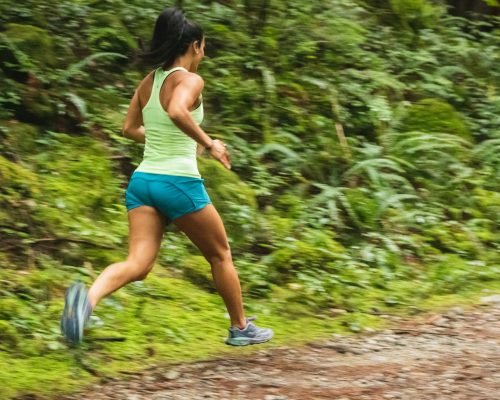 woman in white tank top running on dirt road during daytime