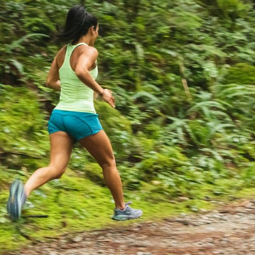 woman in white tank top running on dirt road during daytime