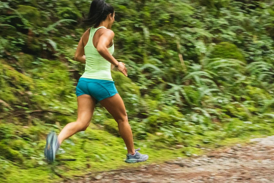 woman in white tank top running on dirt road during daytime