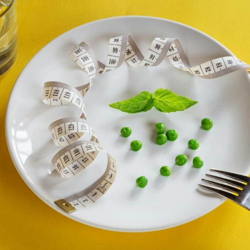 DASH Diet - A white plate topped with peas and measuring tape