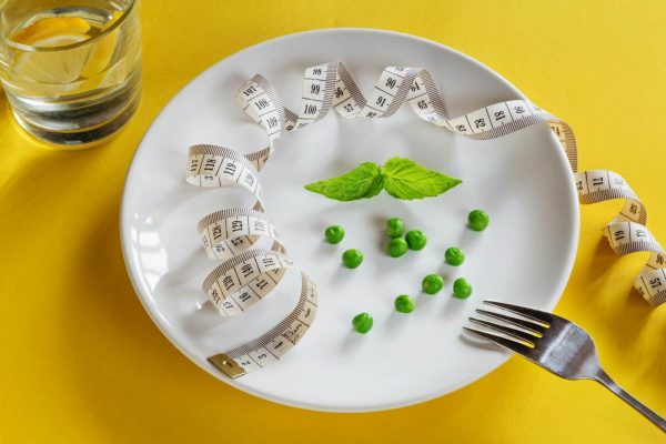 DASH Diet - A white plate topped with peas and measuring tape