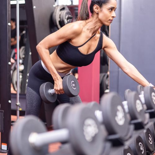A woman doing a squat with dumbbells in a gym