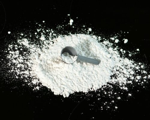 a scoop of powder next to a scoop of sugar