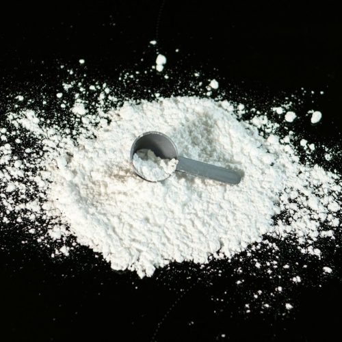 a scoop of powder next to a scoop of sugar